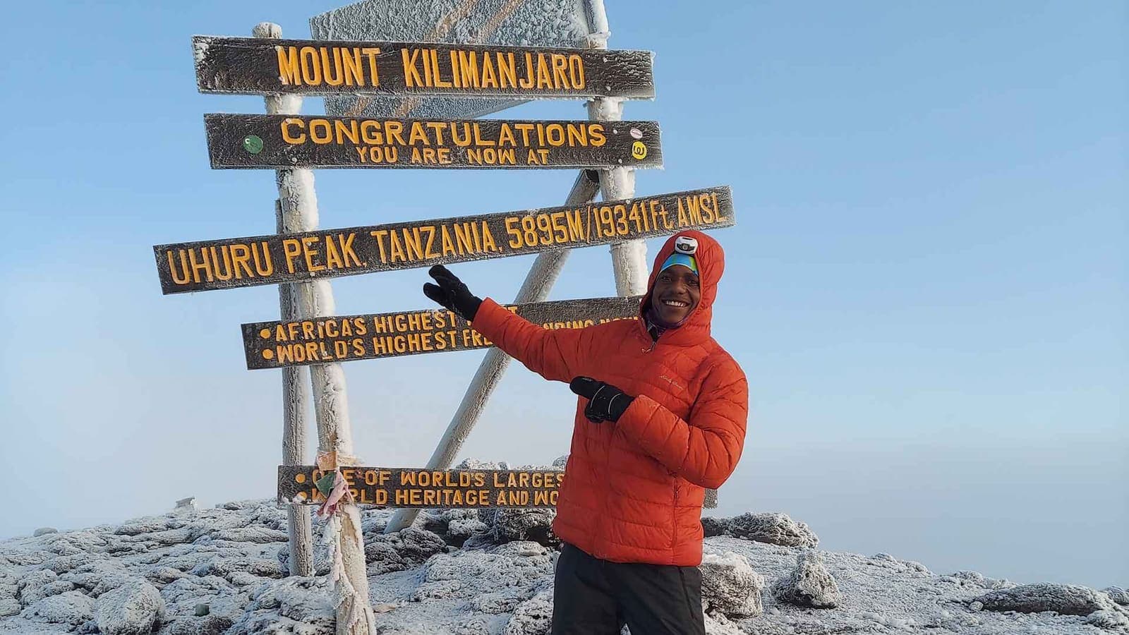 A climber at the Uhuru Peak sign on Mount Kilimanjaro